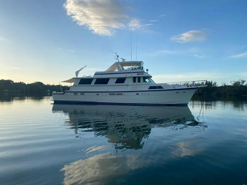 Slide: The Image of 1986 Hatteras 72 Motor Yacht on calm water at sunset. - 0