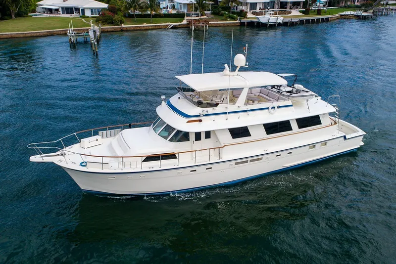 Slide: The Image of 1986 Hatteras 72 Motor Yacht cruising on a calm waterway near waterfront homes. - 1