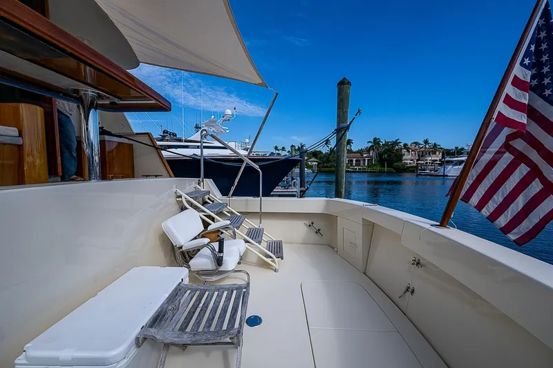 Slide: The Image of 1986 Hatteras 72 Motor Yacht deck with chairs, American flag, and waterfront view. - 10