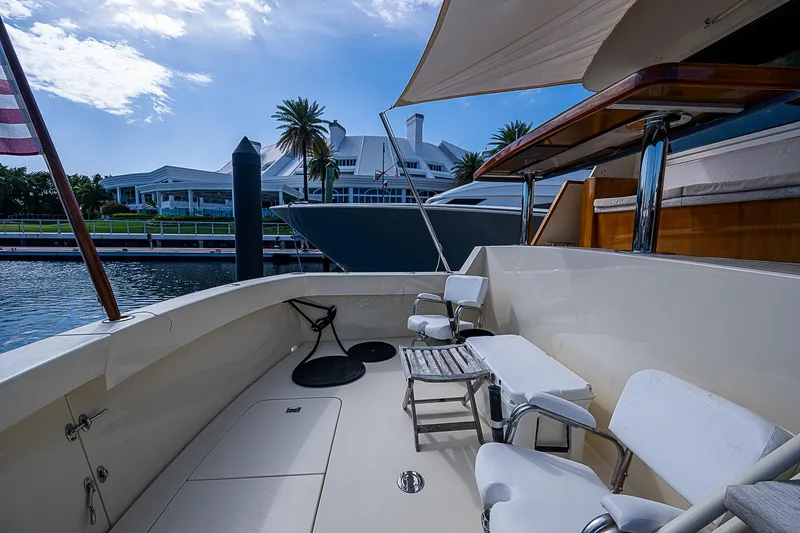 Slide: The Image of 1986 Hatteras 72 Motor Yacht deck with seating, docked near waterfront homes. - 11