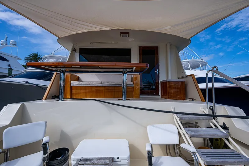 Slide: The Image of 1986 Hatteras 72 Motor Yacht deck with seating and ladder under a clear sky. - 12