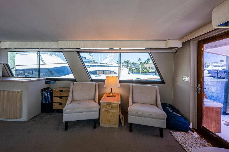 Slide: The Image of Interior of 1986 Hatteras 72 Motor Yacht with chairs and a lamp by large windows. - 26