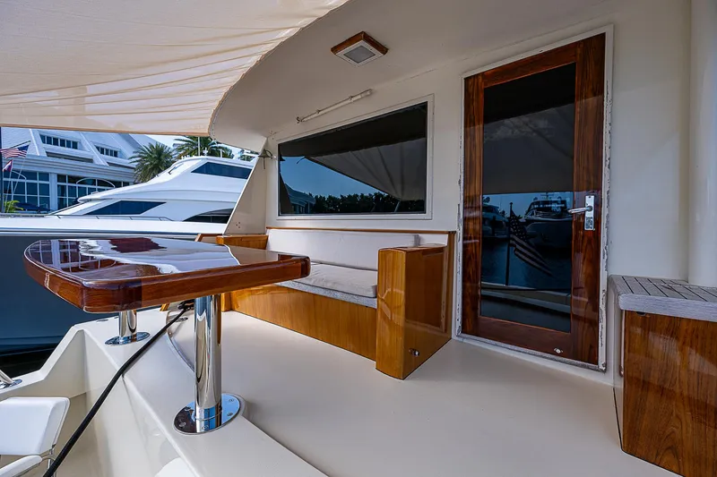 Slide: The Image of Elegant 1986 Hatteras 72 Motor Yacht deck with polished wood table and seating area. - 7