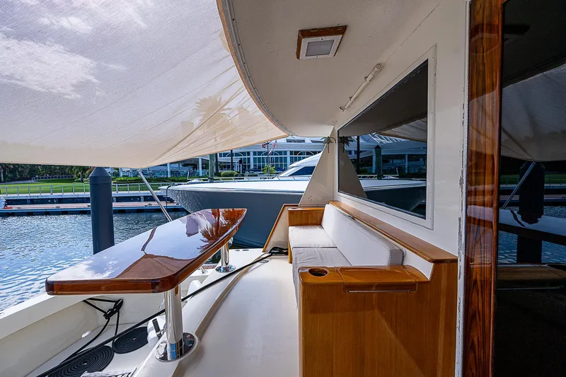 Slide: The Image of Luxurious 1986 Hatteras 72 Motor Yacht with elegant outdoor seating and polished wooden table. - 8