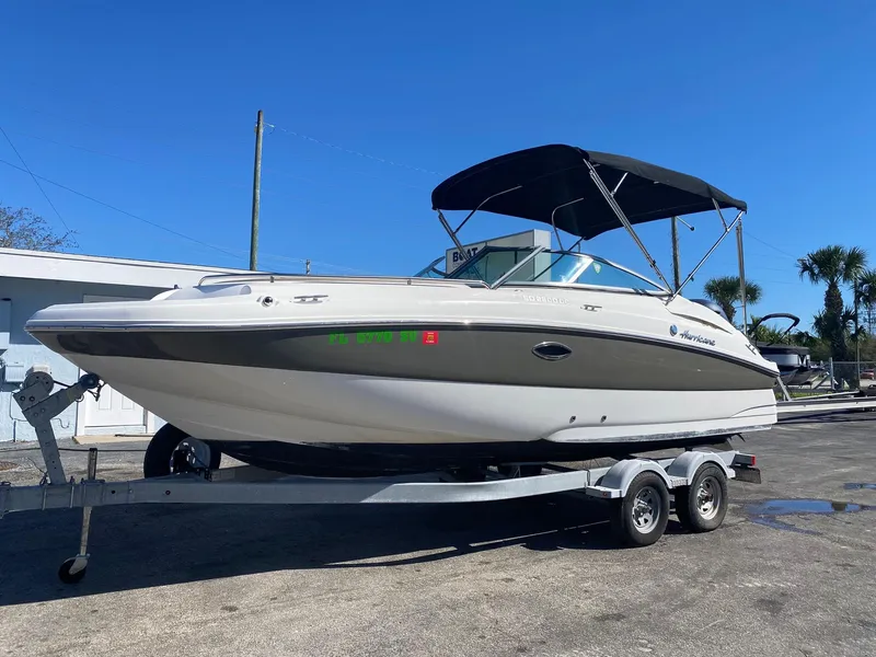 Slide: The Image of 2017 Hurricane SunDeck 2200 DC OB boat on a trailer with a black canopy. - 0