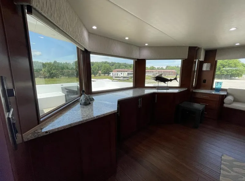Slide: The Image of Interior of a 2015 Stardust Cruisers 20' x 106' houseboat with large windows and wooden cabinetry. - 6