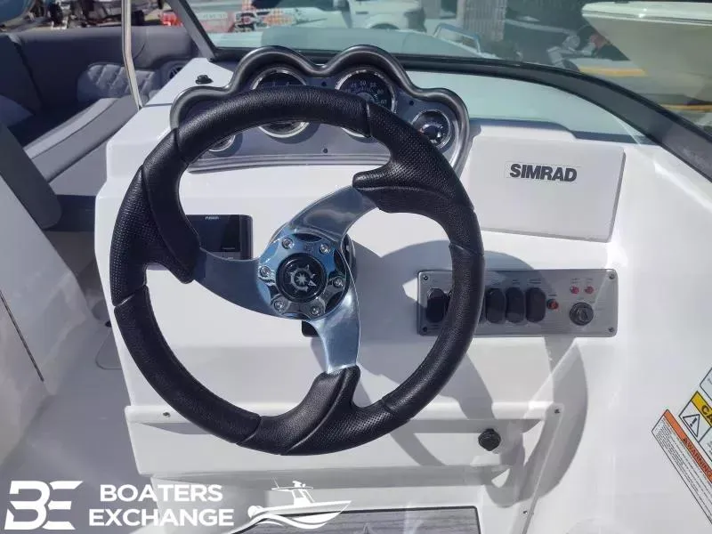 Slide: The Image of 2024 NauticStar 223 DC boat dashboard with steering wheel and Simrad display. - 7