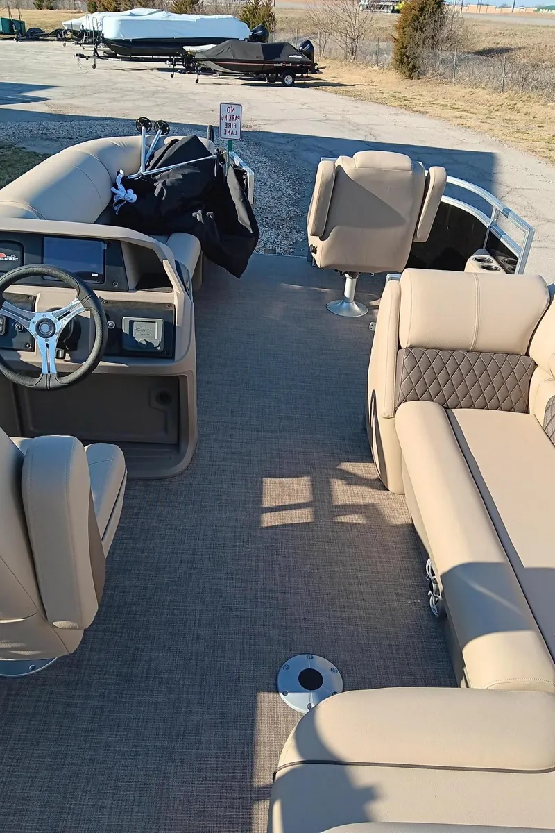 Slide: The Image of 2024 Sun Tracker SportFish 20 DLX pontoon boat interior with beige seating and steering console. - 6