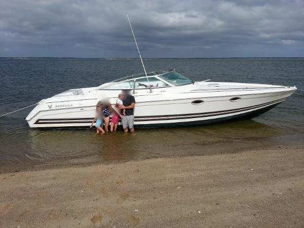 Slide: The Image of Family enjoying a day by a 2000 Formula 33SS boat on a sandy beach. - 12