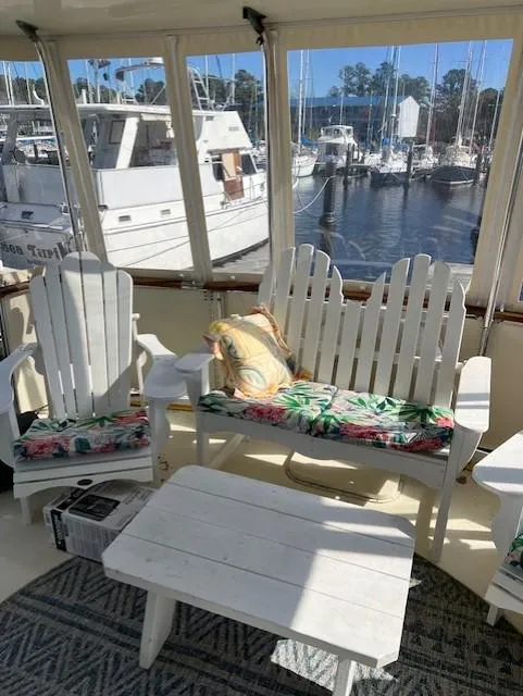 Slide: The Image of 1971 Hatteras 43 Double Cabin yacht interior with white seating, floral cushions, and marina view. - 13