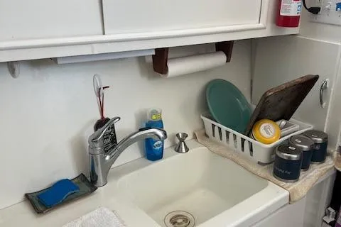 Slide: The Image of 1971 Hatteras 43 Double Cabin kitchen sink with dishes and cleaning supplies. - 28