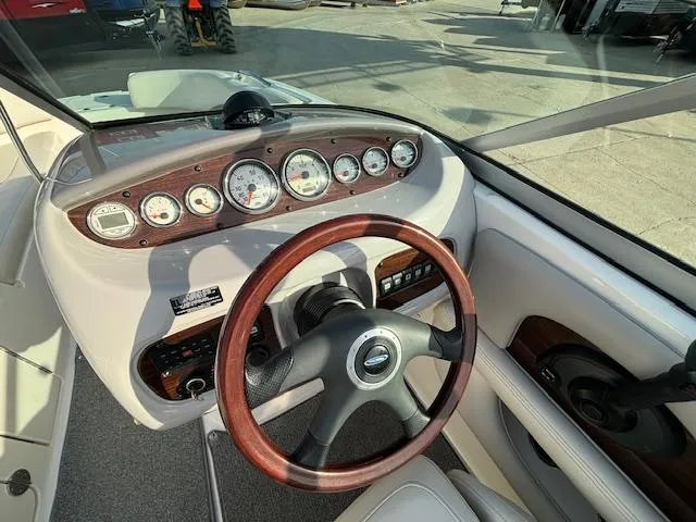 Slide: The Image of 2005 Chaparral 216 SUNSETTA boat dashboard with wood-trimmed steering wheel and gauges. - 23