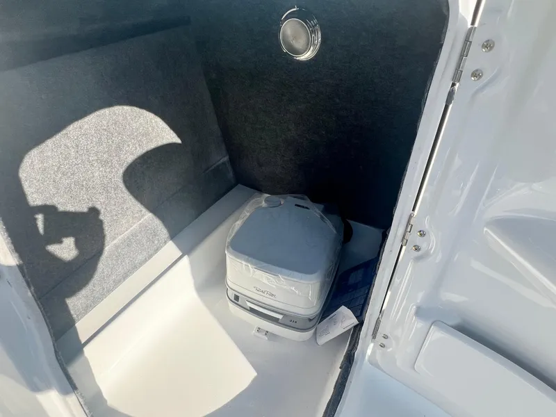 Slide: The Image of 2024 NauticStar 223DC boat interior storage compartment with portable toilet. - 7