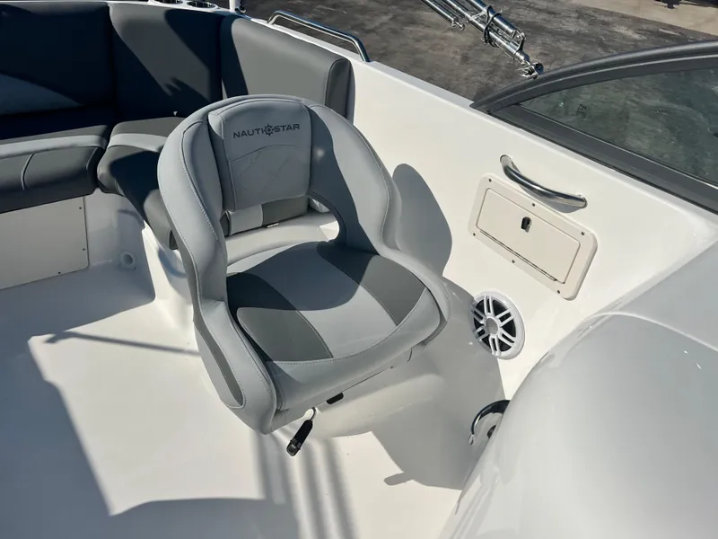 Slide: The Image of 2024 NauticStar 223DC boat interior with gray captain's chair and storage compartment. - 9