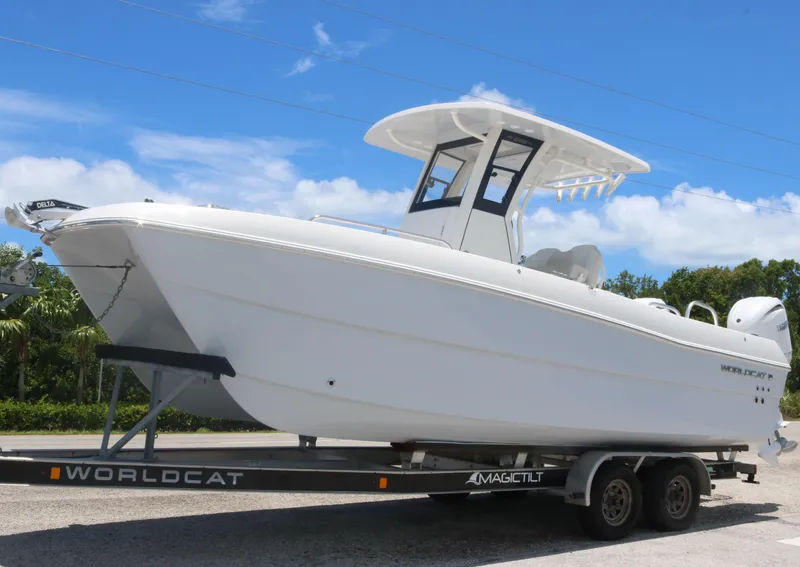 The Image of 2025 World Cat 235TE boat on a Magic Tilt trailer under a clear blue sky. - 0