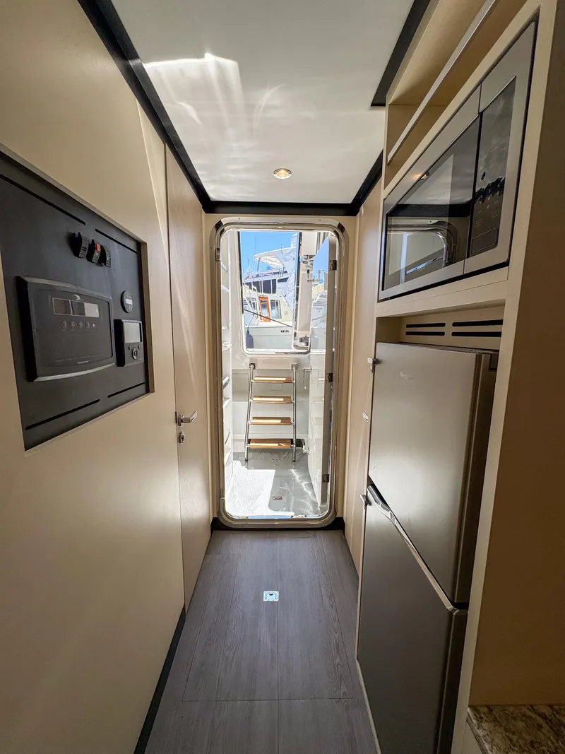 Slide: The Image of 2024 Ocean Alexander 32L yacht interior hallway with modern appliances and exterior view. - 44