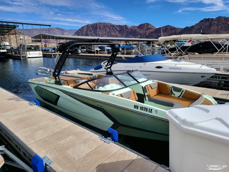 Slide: The Image of 2022 Heyday WT-Surf boat docked at a marina with scenic mountain backdrop. - 5