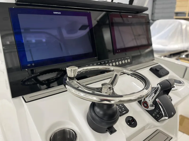 Slide: The Image of 2024 Sea Pro 322 DLX boat helm with dual Simrad displays and stainless steel steering wheel. - 10