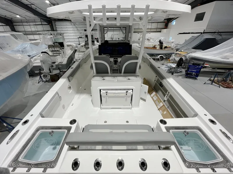 Slide: The Image of 2024 Sea Pro 322 DLX boat interior in a showroom, featuring dual seats and storage compartments. - 9