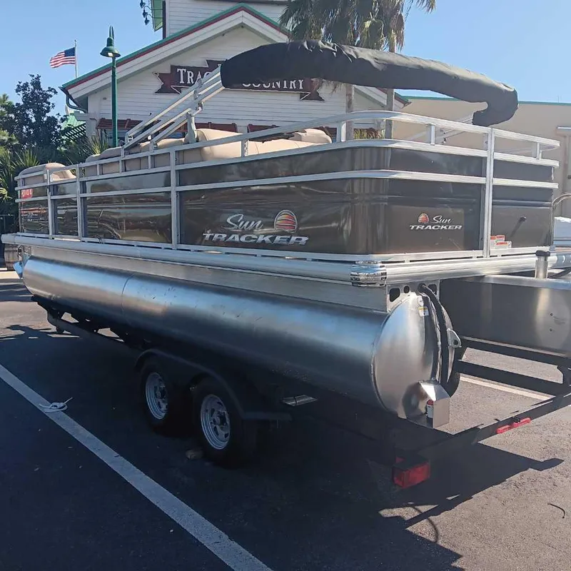 Slide: The Image of 2024 Sun Tracker SportFish 22 DLX pontoon boat on a trailer in a parking lot. - 6