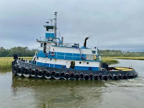 Slide: The Image of A 1961 Commercial Model Bow Tug navigating a calm river, surrounded by lush greenery. - 0