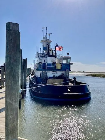 Slide: The Image of Vintage 1961 Model Bow Tugboat docked, American flag waving, sunny day. - 1