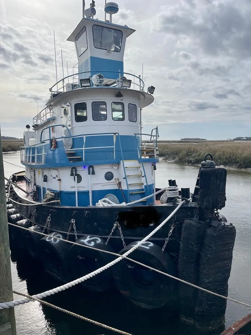 Slide: The Image of 1961 Commercial Model Bow Tug docked in a calm waterway under a cloudy sky. - 3