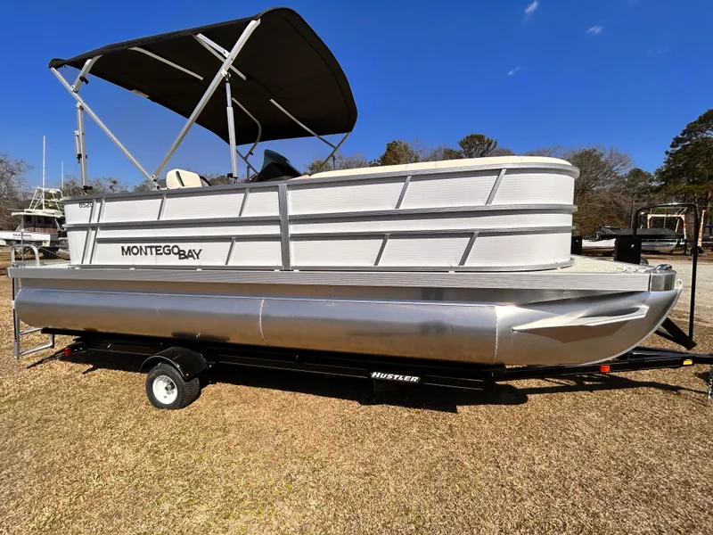The Image of 2023 Montego Bay 8520 pontoon boat on trailer, sunny day, grassy area. - 1