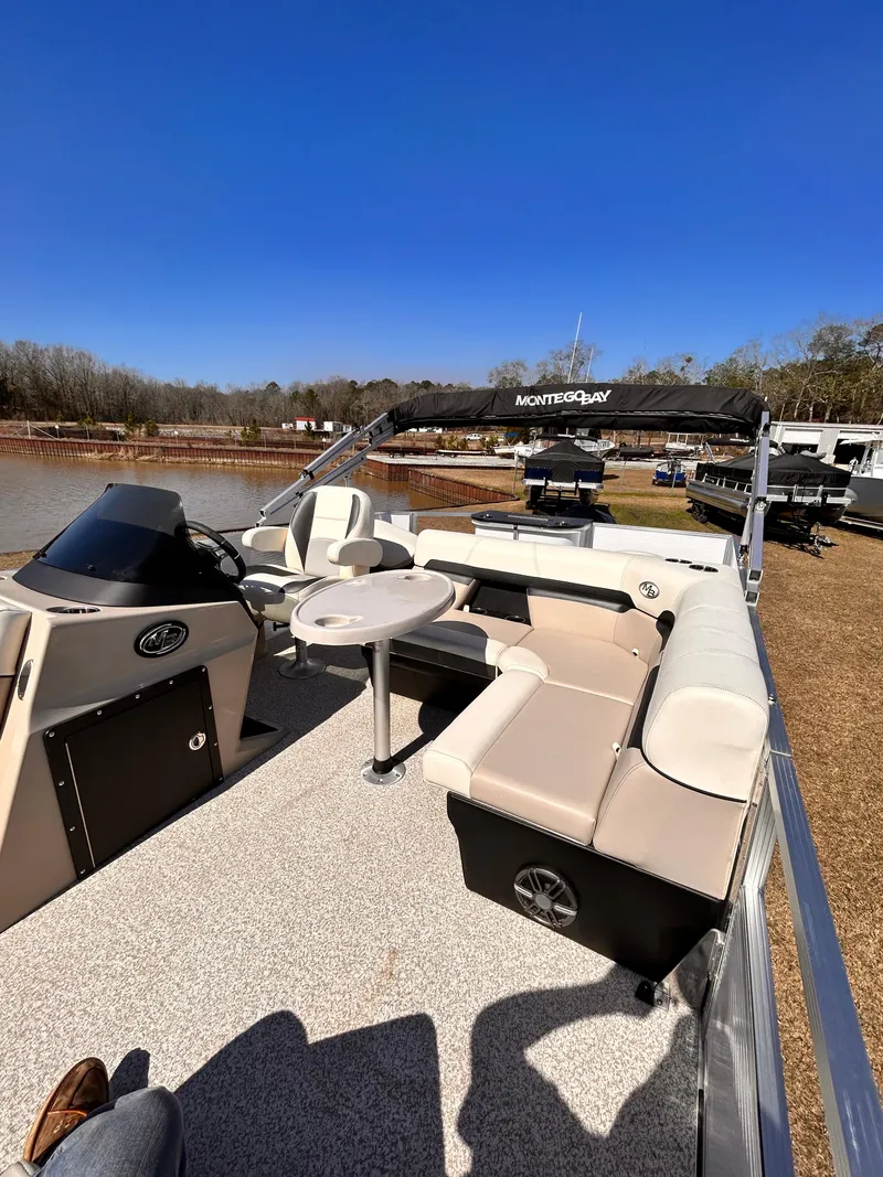 Slide: The Image of 2023 Montego Bay 8520 pontoon boat with seating and table, docked by a lake. - 13