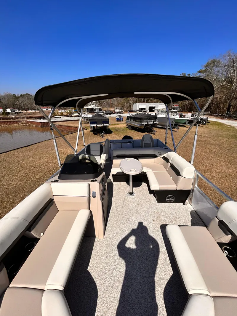 Slide: The Image of 2023 Montego Bay 8520 pontoon boat with spacious seating and canopy, parked on grass. - 5