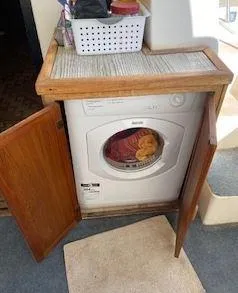 Slide: The Image of Washing machine inside a 1981 Blue Water Coastal Cruiser with wooden cabinet doors open. - 10