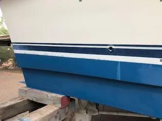 Slide: The Image of 1981 Blue Water Coastal Cruiser boat hull with blue and white stripes on wooden supports. - 15