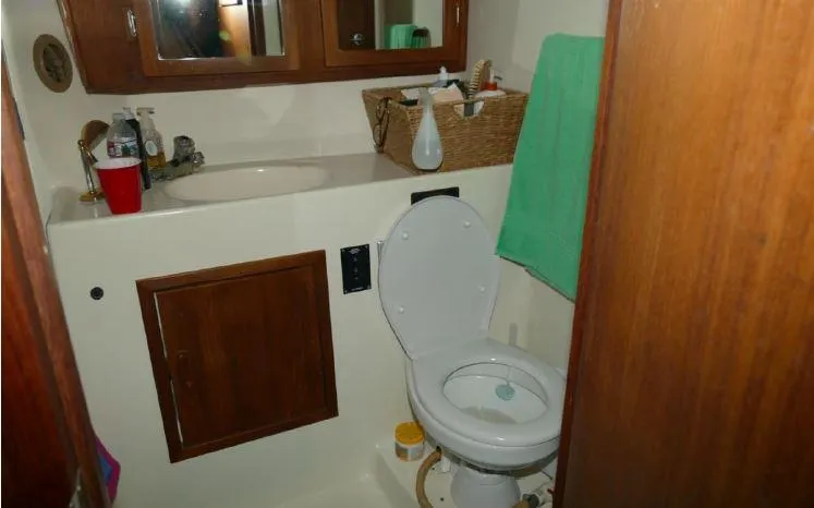 Slide: The Image of 1981 Blue Water Coastal Cruiser bathroom with wooden cabinets and white fixtures. - 5
