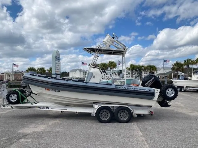 Slide: The Image of 2020 Ocean Craft Marine 24 boat on trailer, parked outdoors under cloudy sky. - 3