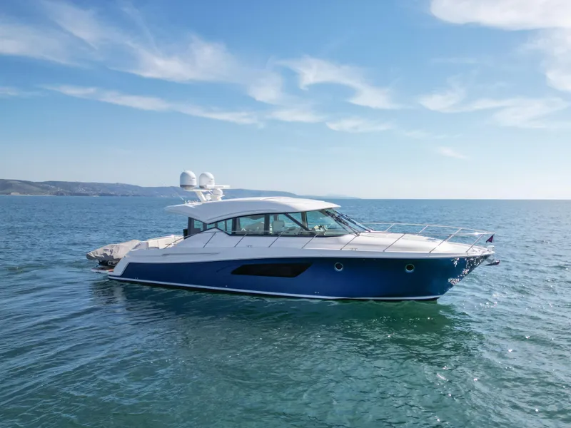 Slide: The Image of 2022 Tiara Yachts 53 Coupe cruising on open water under a clear blue sky. - 0