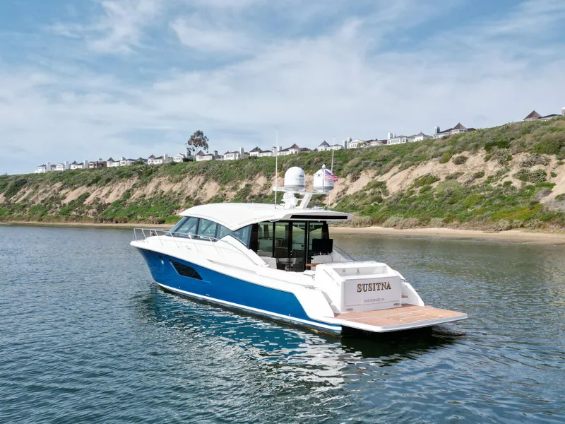 Slide: The Image of 2022 Tiara Yachts 53 Coupe on serene water near a scenic coastline. - 14