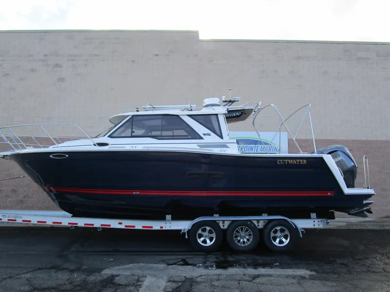 Slide: The Image of 2024 Cutwater C-288 C boat on trailer, sleek design, navy blue hull. - 2