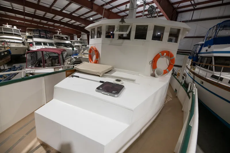 Slide: The Image of 1993 Custom Steel Trawler in indoor marina, white exterior, life rings, and spacious deck. - 10