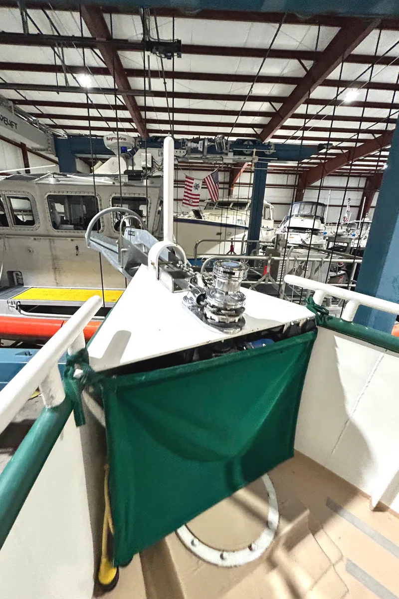 Slide: The Image of 1993 Custom Steel Trawler in a boatyard, showcasing deck equipment and green canvas. - 12