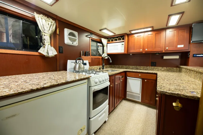 Slide: The Image of 1993 Custom Steel Trawler kitchen with granite countertops and wooden cabinets. - 23