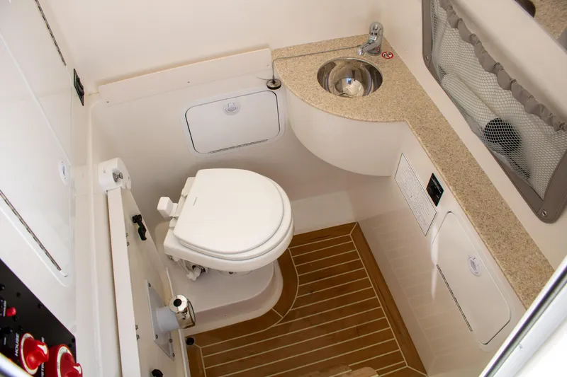 Slide: The Image of 2021 Regulator 28 boat bathroom with toilet, sink, and wooden floor. - 23