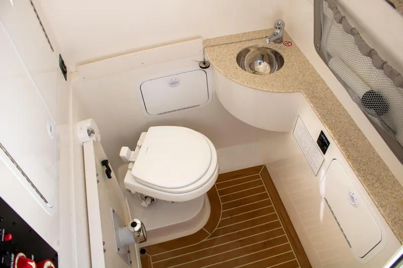 Slide: The Image of 2021 Regulator 28 boat bathroom with toilet, sink, and wood-style flooring. - 24