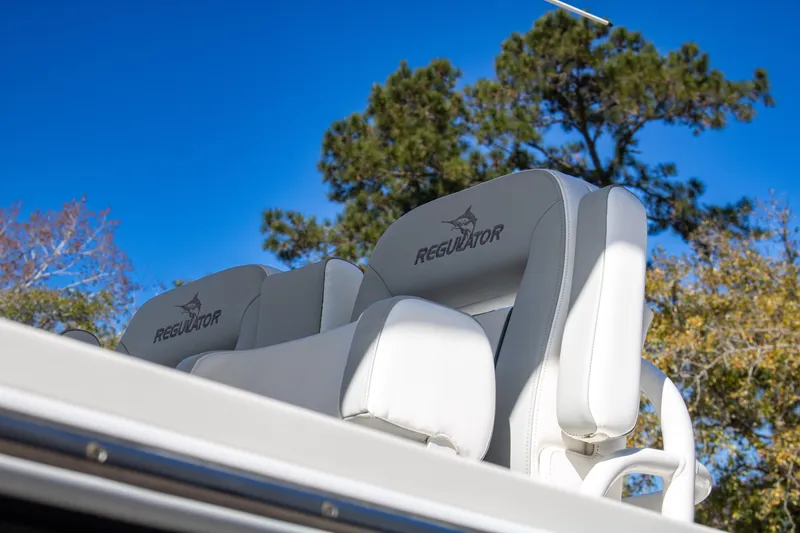 Slide: The Image of 2021 Regulator 28 boat seats against a clear blue sky and trees. - 6
