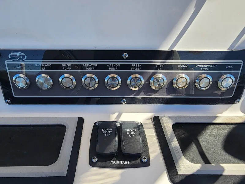 Slide: The Image of Control panel of 2021 Sea Fox 228 Commander boat with labeled switches and trim tabs. - 16