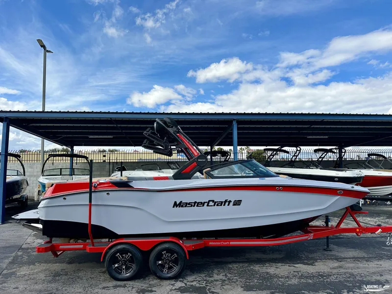 Slide: The Image of 2024 MasterCraft XT24 boat on trailer under blue sky. - 0