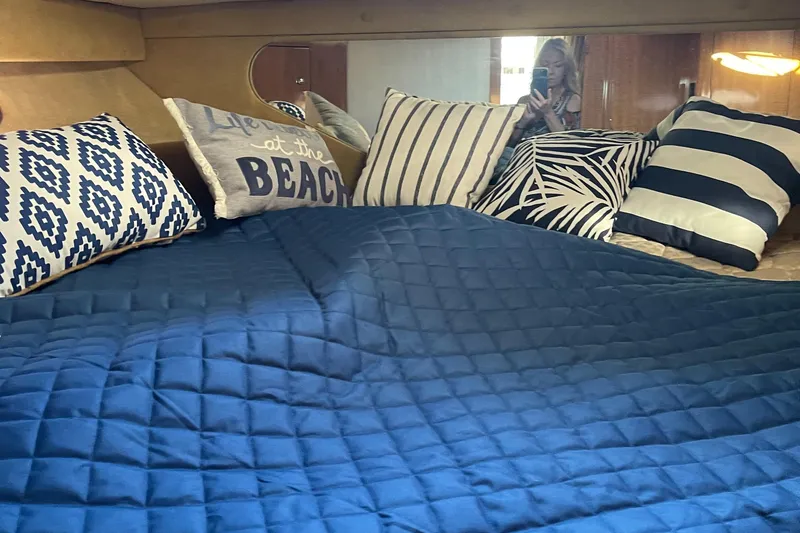 Slide: The Image of Interior cabin of 2004 Regal Commodore 3560 IO with blue bedding and decorative pillows. - 13