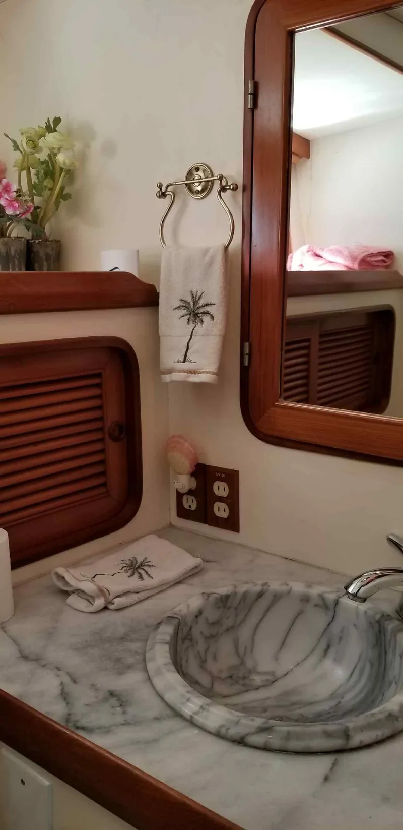 Slide: The Image of 1984 Angel Defever LRC yacht bathroom with marble sink, wooden accents, and palm-themed decor. - 18