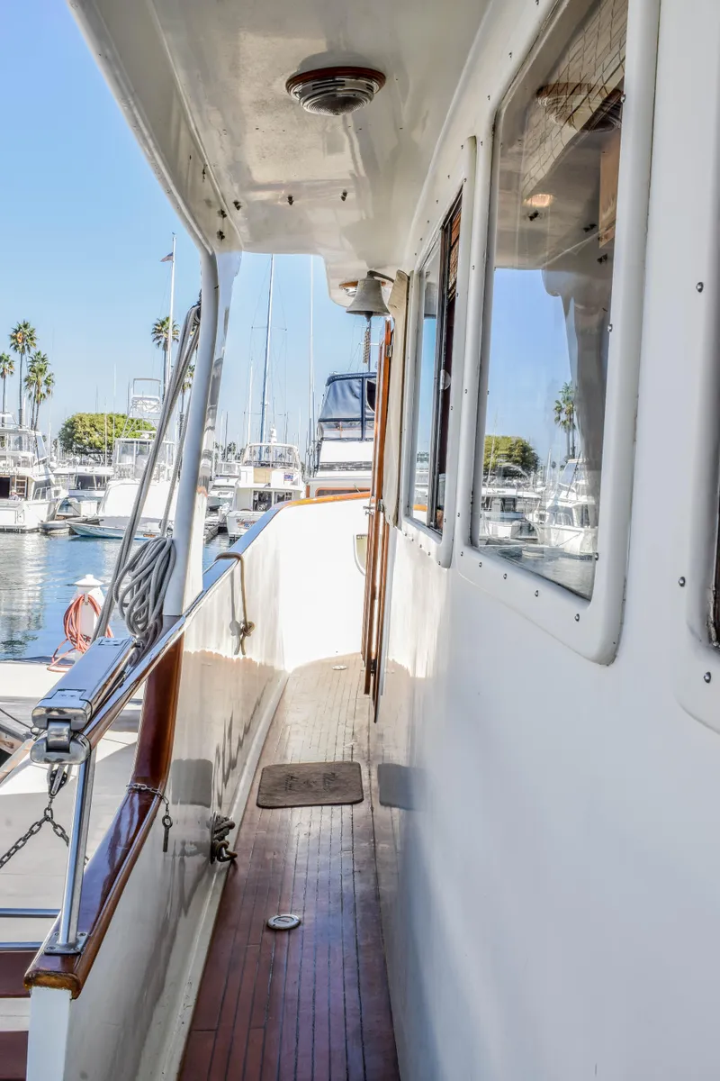 Slide: The Image of 1984 Angel Defever LRC yacht deck with wooden flooring, docked at a marina. - 22