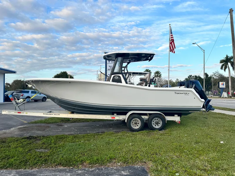 Slide: The Image of 2024 Tidewater 256 LXF boat on a trailer, parked outdoors with an American flag in the background. - 3