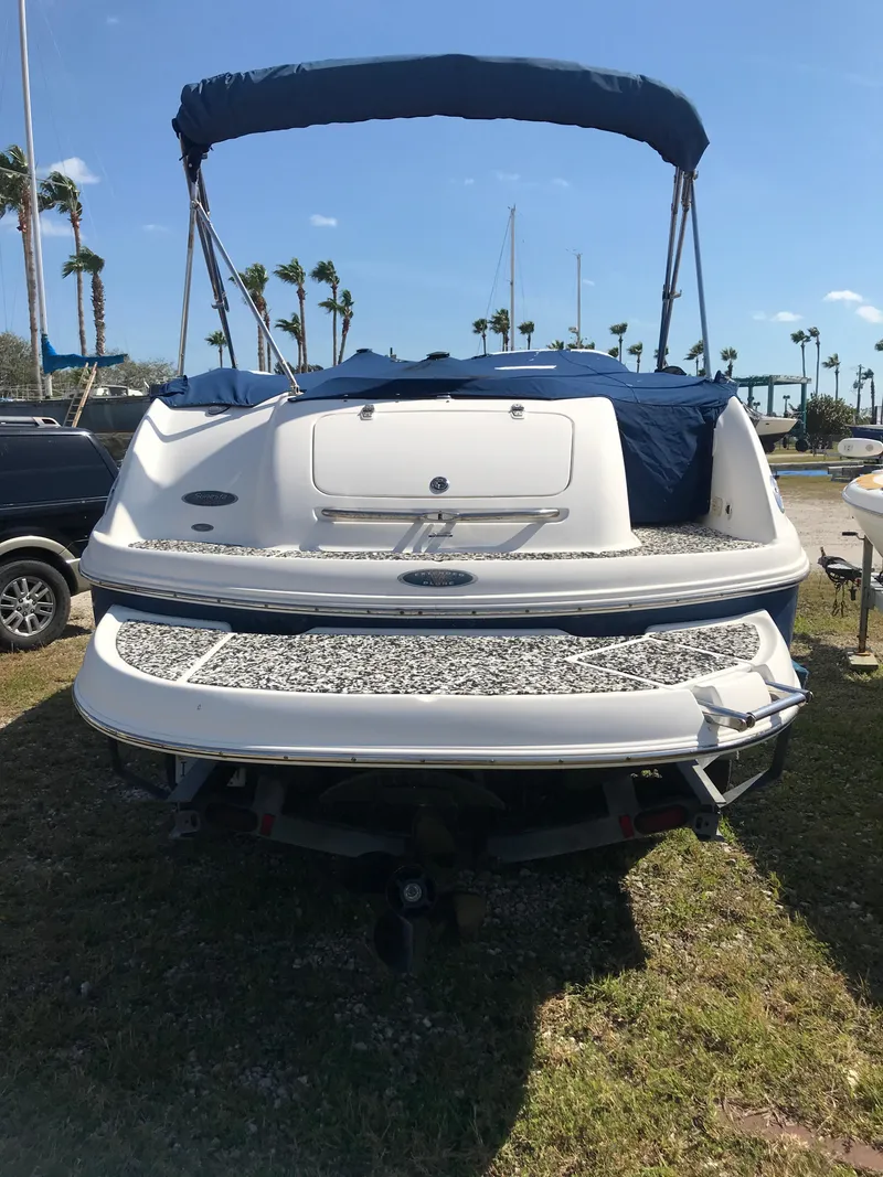 Slide: The Image of 2005 Chaparral Sunesta 252 boat with blue canopy, parked on grass under clear sky. - 3